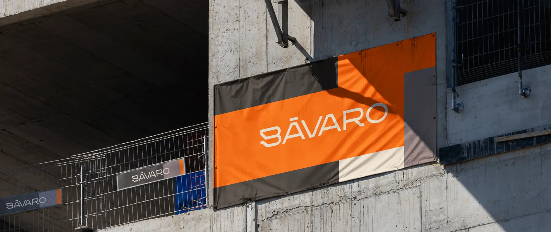 Cartel publicitario naranja y negro con el logo de Edificio Bávaro instalado en la estructura de hormigón de la obra en Puerto Norte.