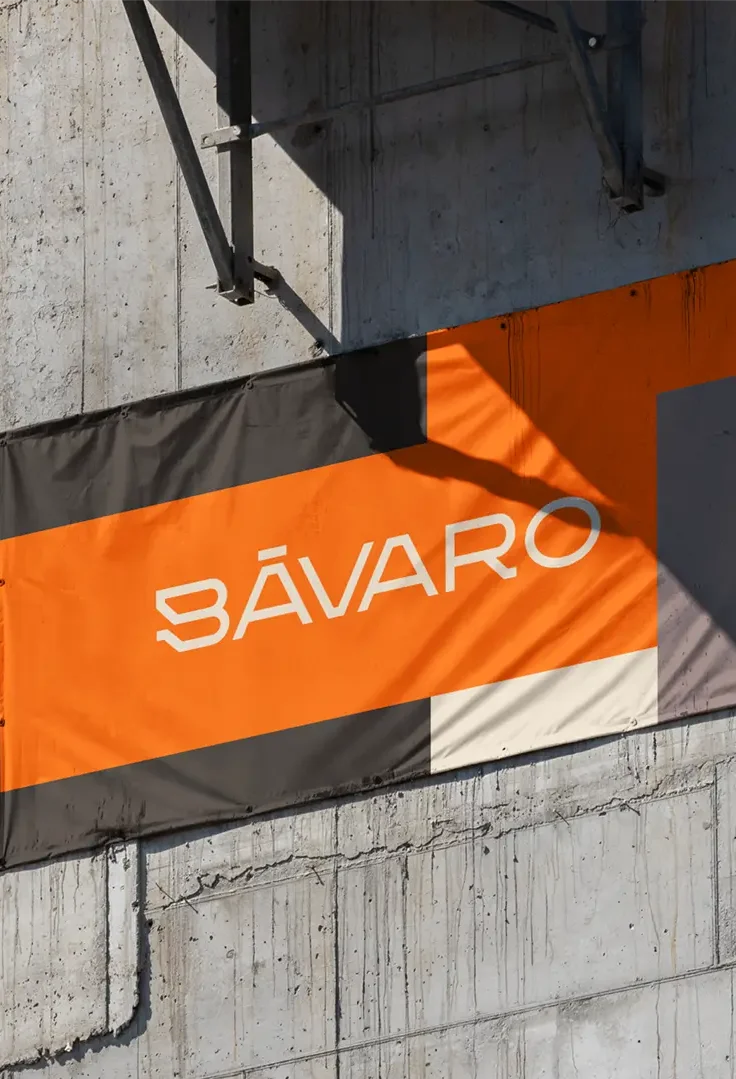 Cartel publicitario naranja y negro con el logo de Edificio Bávaro instalado en la estructura de hormigón de la obra en Puerto Norte.